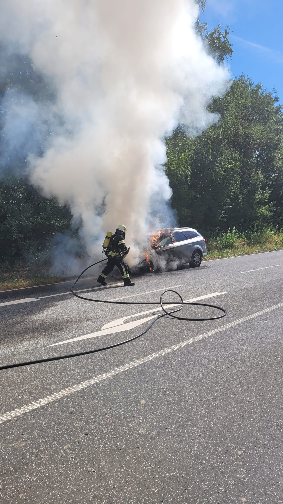 Löscharbeiten an einem brennenden Fahrzeug